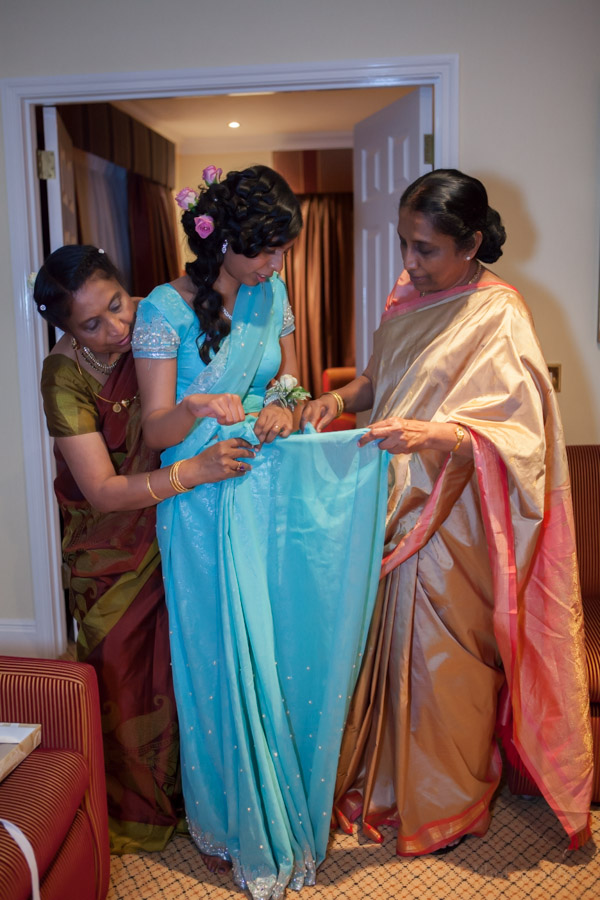 mother helping bride wear a sari